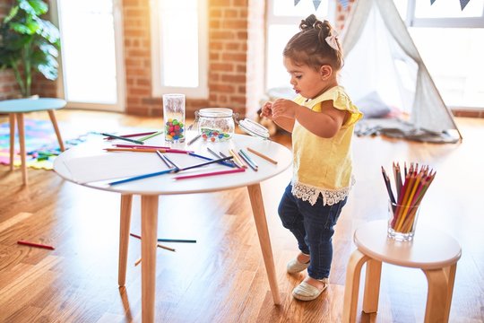 Beautiful toddler standing playing with chocolate colored balls on the table at kindergarten