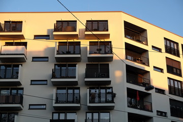 Modernes Wohnhaus in Beige und Naturfarben mit Balkon vor blauem Himmel im Licht der Abendsonne in...