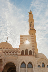 Fototapeta na wymiar One of the main mosques in touristic city of Sharm el Sheikh, Egypt. Islamic faith concept. Against the backdrop of a beautiful blue sky with clouds. vertical photo