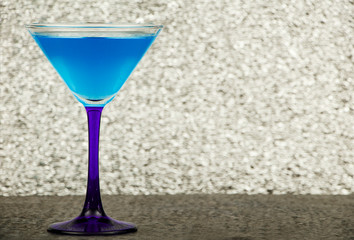 Blue cocktail in a glass for martini on a gray background. Blue cocktail with martini on a gray stone background.