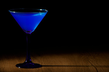 Blue cocktail in a glass for martini on a gray background. Blue cocktail with martini on a gray stone background.