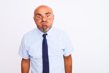 Middle age businessman wearing tie standing over isolated white background puffing cheeks with funny face. Mouth inflated with air, crazy expression.