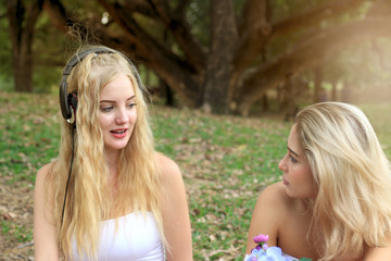 Happy relaxing friends on picnic in park, two young beautiful teen girls having fun while spending time together in the garden, woman outdoor friendship concept.