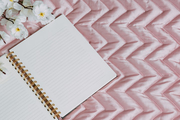 Beautiful white eustoma flower and notebook on pink background