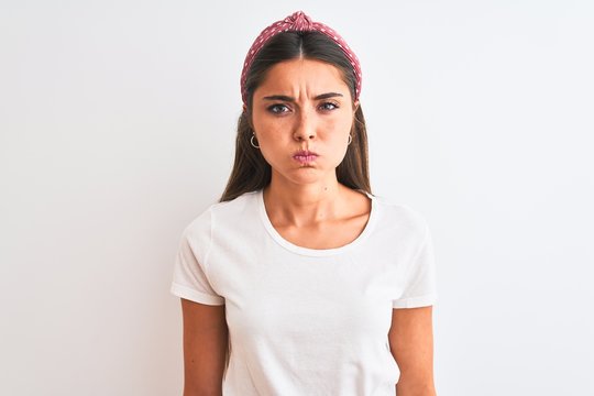 Young beautiful woman wearing casual t-shirt and diadem over isolated white background puffing cheeks with funny face. Mouth inflated with air, crazy expression.