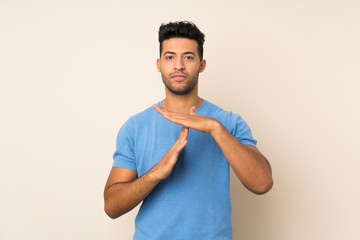 Young handsome man over isolated background making time out gesture