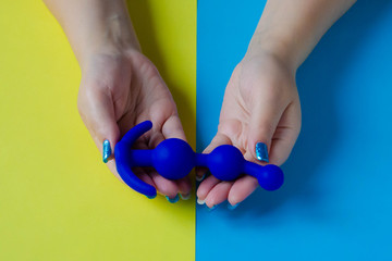 Sex toy. Butt plug in the hand. Blue anal toy on a color background. Useful for adult, sex shop
