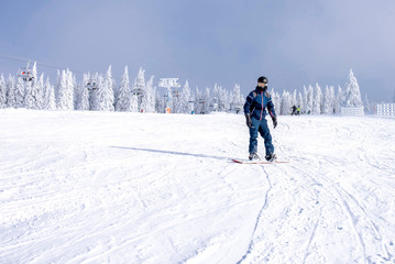 Active male snowboarder enjoy riding snowboard down the slope with beautiful winter landscape in...