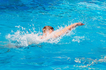 Young guy swims in the pool. Summer vacation at the resort_