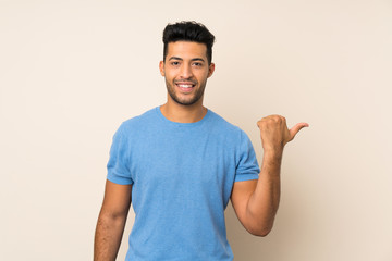 Young handsome man over isolated background pointing to the side to present a product