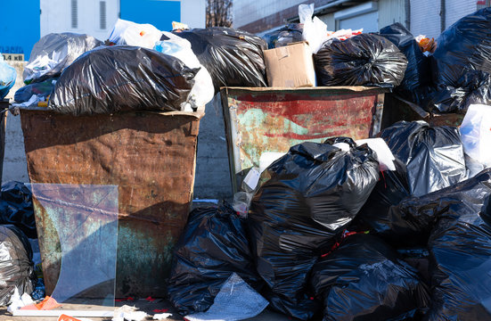 Crowded trash bins, trash in the street.