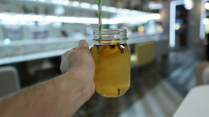 The guy holds a glass of mulled wine or tea in his hand. Restaurant, cafe, bar, warm evening drink from a straw