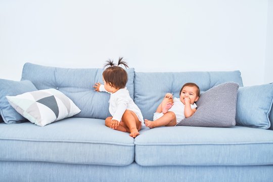 Beautiful infant happy girls playing together at home kindergarten sitting on the sofa