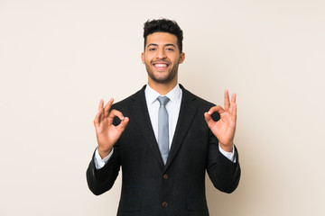 Young handsome businessman man over isolated background showing an ok sign with fingers