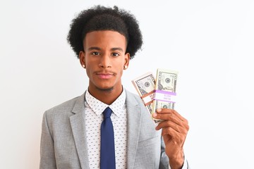 Young african american businessman holding dollars standing over isolated white background with a confident expression on smart face thinking serious