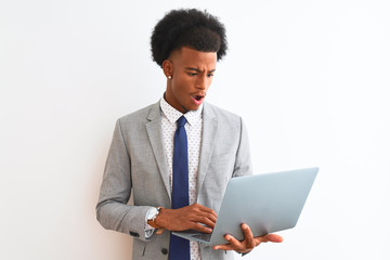 Young african american businessman using laptop standing over isolated white background scared in shock with a surprise face, afraid and excited with fear expression