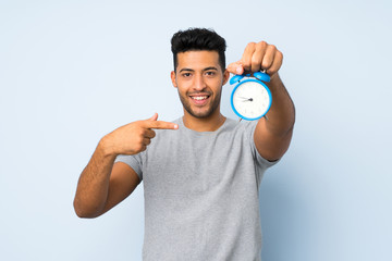 Young handsome man over isolated background holding vintage alarm clock