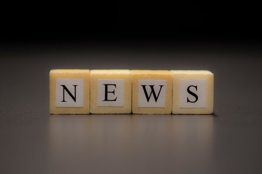 The word NEWS written on wooden cubes isolated on a black background...