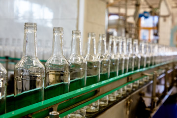 Bottles are moving on a conveyor belt at a factory for the production of Russian vodka - obrazy, fototapety, plakaty