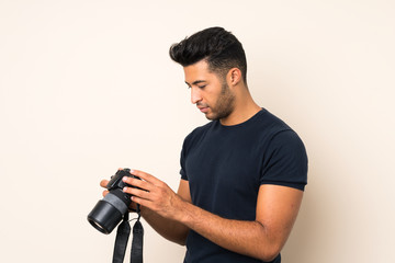 Young handsome man over isolated background with a professional camera