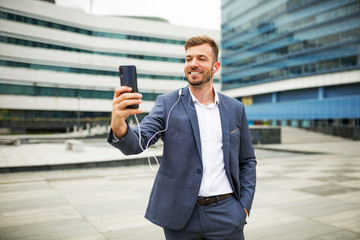 Handsome businessman in suit using smartphone at street