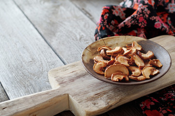 Sliced and dried Apple lies in a ceramic plate on a wooden Board. Apple chips.Horizontal layout, close-up, copy space.