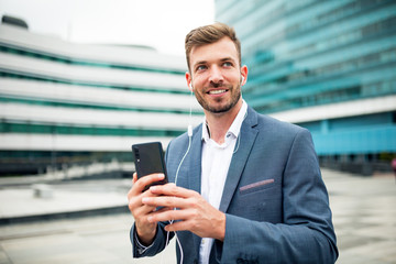 Handsome businessman in suit using smartphone at street