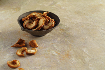 Dried Apple slices in a ceramic Cup and on a textured yellow background, Apple dried fruits are scattered nearby. Apple chips, horizontal position, copy space.