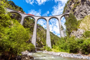 Papier Peint photo Viaduc de Landwasser Viaduc de Landwasser, Suisse. Le train rouge circule sur un pont ferroviaire élevé dans les montagnes. Cet endroit est l& 39 emblème des Alpes suisses. Vue panoramique du célèbre chemin de fer.