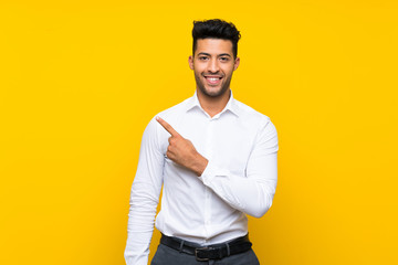 Young handsome man over isolated yellow background pointing finger to the side