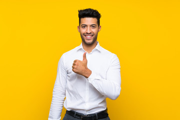 Young handsome man over isolated yellow background giving a thumbs up gesture