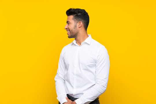 Young handsome man over isolated yellow background looking to the side