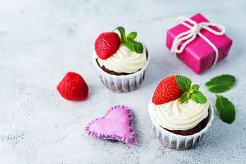 Chocolate cupcakes with cream cheese frosting, mint leaves and strawberries