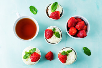 Chocolate cupcakes with cream cheese frosting, mint leaves and strawberries