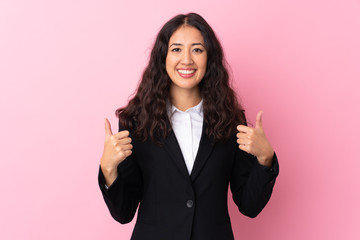 Mixed race business woman over isolated pink background giving a thumbs up gesture