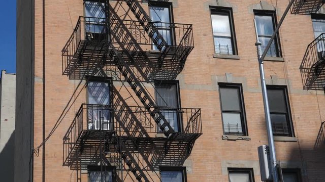 Slow motion drive past apartment with fire escapes. Queens, New York City.