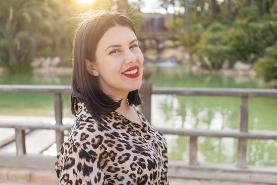 Young beautiful woman with red lips smiling happy at garden