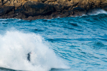 Surfer swallowed by a big wave on a beach on the north coast of Spain