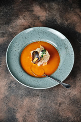 pumpkin soup with mussels and pieces of bruschetta on a dark background