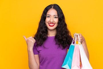 Spanish Chinese woman with shopping bag over isolated background pointing to the side to present a product