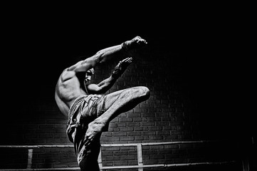 Thai boxer in the ring hits with a knee. The concept of sports, gyms, boxing clubs.