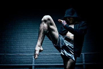 Thai boxer in the ring hits with a knee. The concept of sports, gyms, boxing clubs.