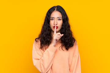 Spanish Chinese woman over isolated yellow background showing a sign of silence gesture putting finger in mouth