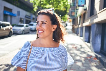 Young beautiful woman smiling happy walking on city streets on a sunny day of summer