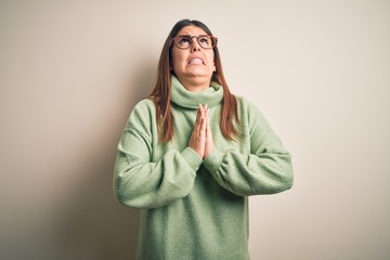 Young beautiful woman wearing casual sweater standing over isolated white background begging and...