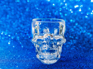 Glass in the shape of a human skull on a blue background