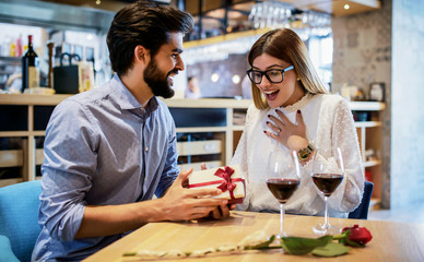 Birthday present for a girlfriend. Romantic couple sitting in the cafe and drinking red wine. Dating, love, relationships