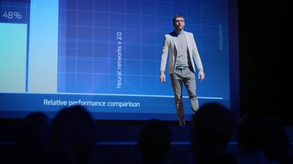 Successful Male Speaker Gets on Stage, Greets Audience and Presentation of the New Product, Shows Infographics, Statistics Animation on Screen. Live Event / Device Release / Start-up Conference