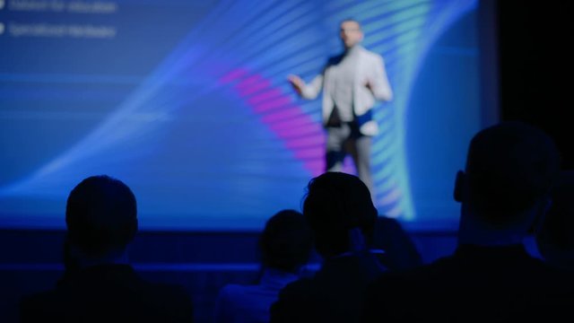 Tech Conference Auditorium Hall, Speaker Does Presentation New Product on Market, Talks about Performance Comparison. Focus on Applauding Audience. Device Release / Start-up Business Conference