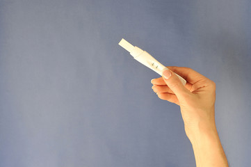 Pregnancy test strip in a female hand. Free space for text. Close-up.